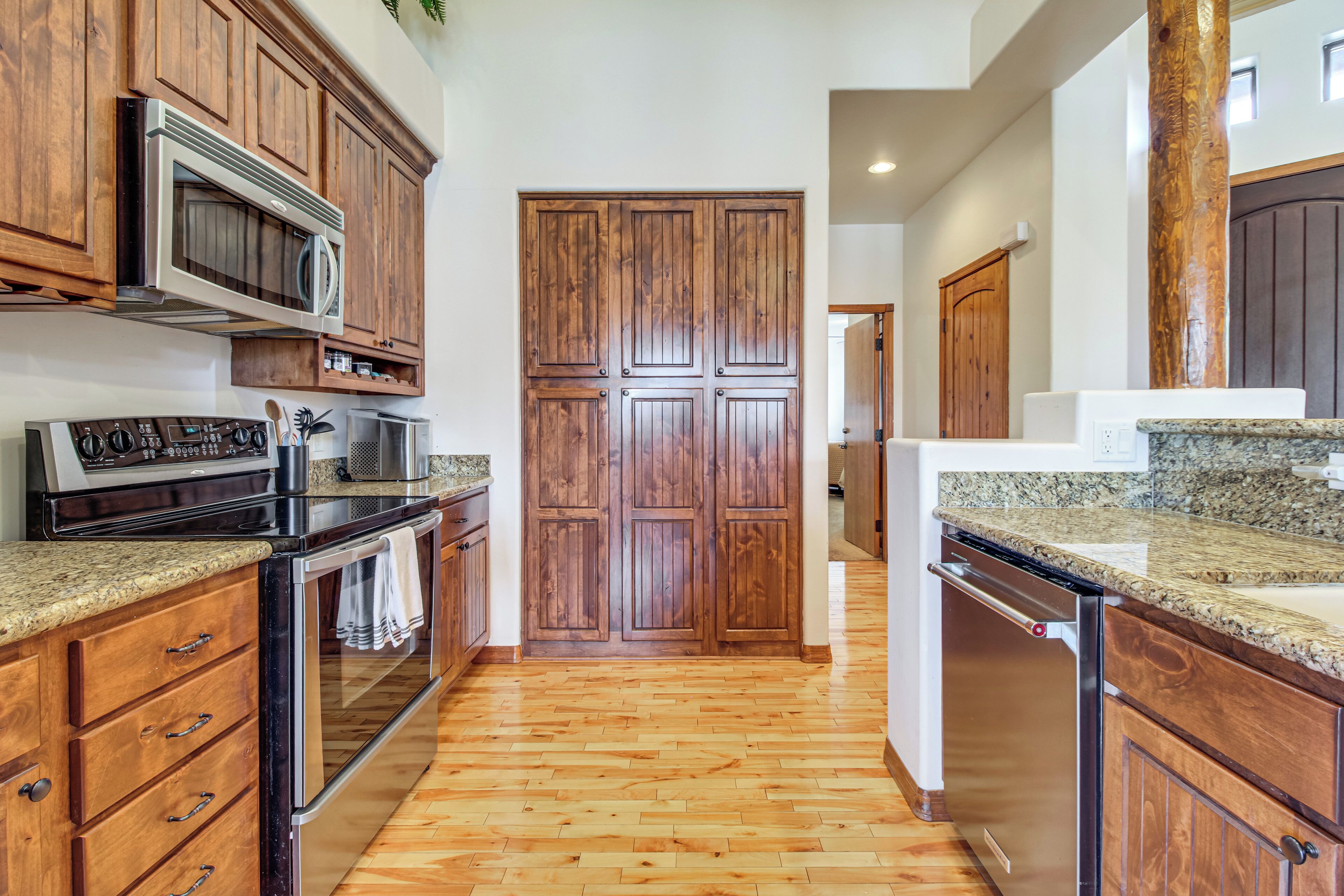 A kitchen with wooden cabinets, a stainless steel oven, a microwave, granite countertops, and a dishwasher.