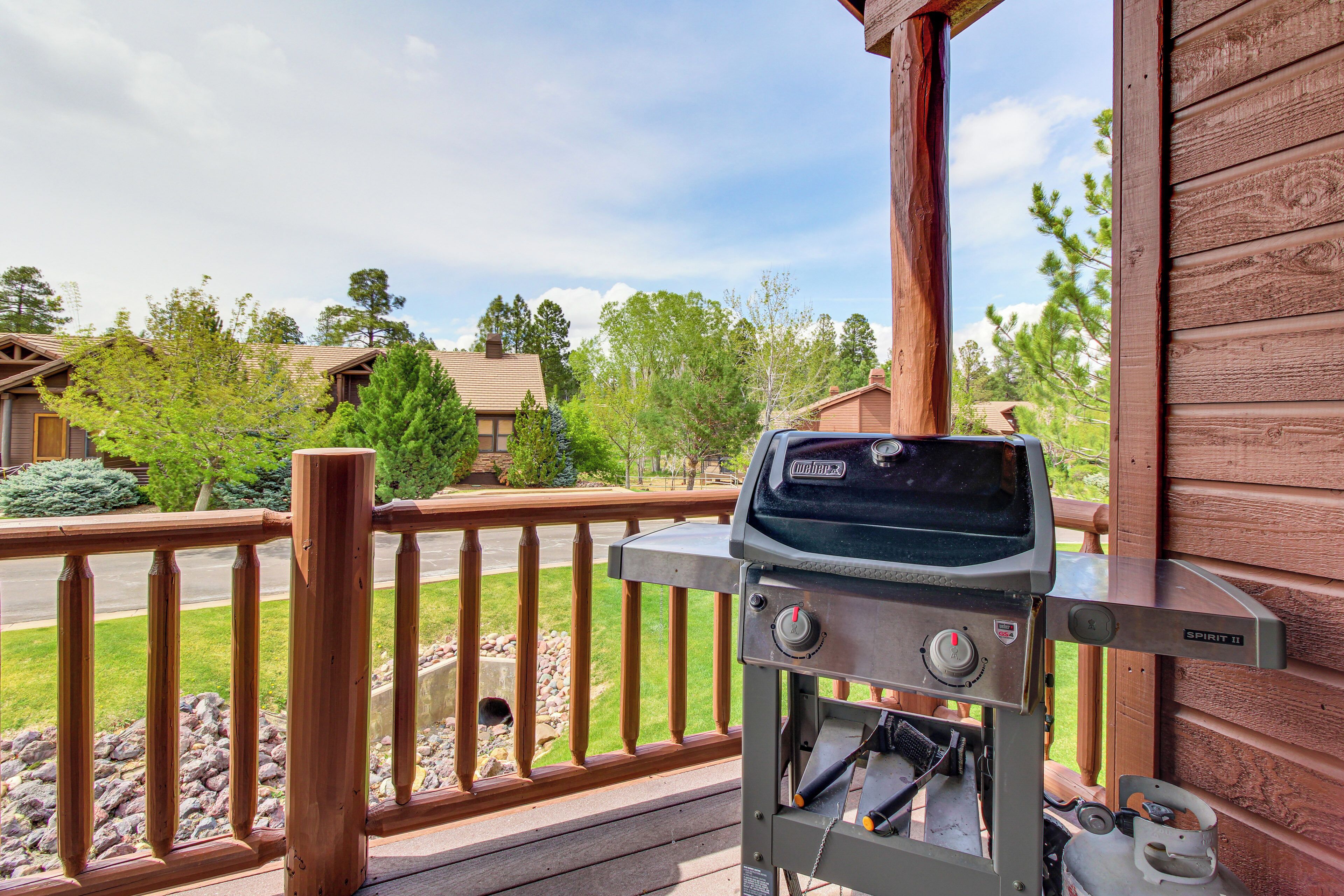 A barbecue grill on a wooden deck with a view of a residential area.