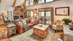 A cozy living room with a stone fireplace, leather sofa, wooden coffee table, and a large window with a view. - Luxe Franklin Home Features Indoor/outdoor Comfort (Franklin)