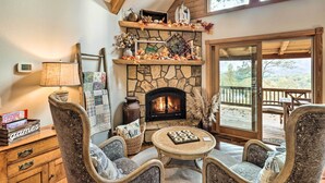 A cozy living room with a stone fireplace, comfortable seating, and a view of the outdoors. - Luxe Franklin Home Features Indoor/outdoor Comfort (Franklin)