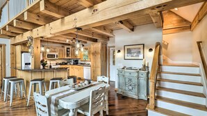 A spacious kitchen with wooden beams, a dining area with white chairs, and a staircase. - Luxe Franklin Home Features Indoor/outdoor Comfort (Franklin)