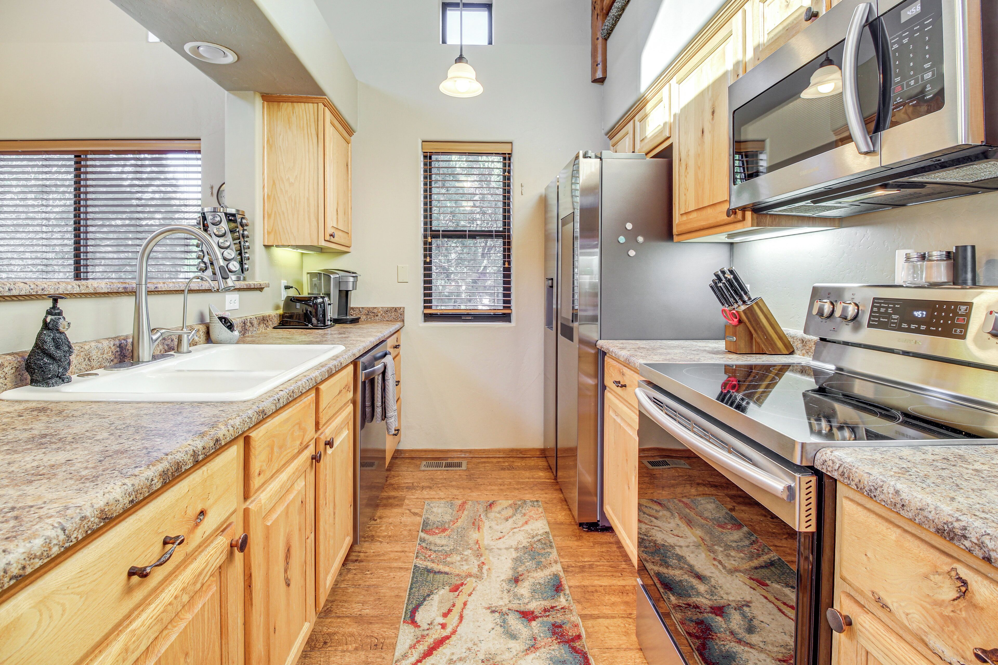 A kitchen with wooden cabinets, stainless steel appliances, granite countertops, and a window with blinds.