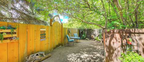 A wooden fence with a sign, a wooden bench, and a planter with green plants.