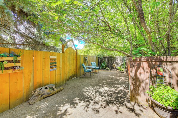 Una cerca de madera con un letrero, un banco de madera y una jardinera con plantas verdes.