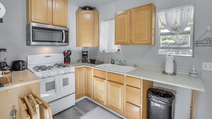 A compact kitchen with wooden cabinets, a stainless steel microwave, a gas stove, and a white sink. - 2 Mi to Dtwn Atascadero! Cozy Cottage w/ Yard (Atascadero)