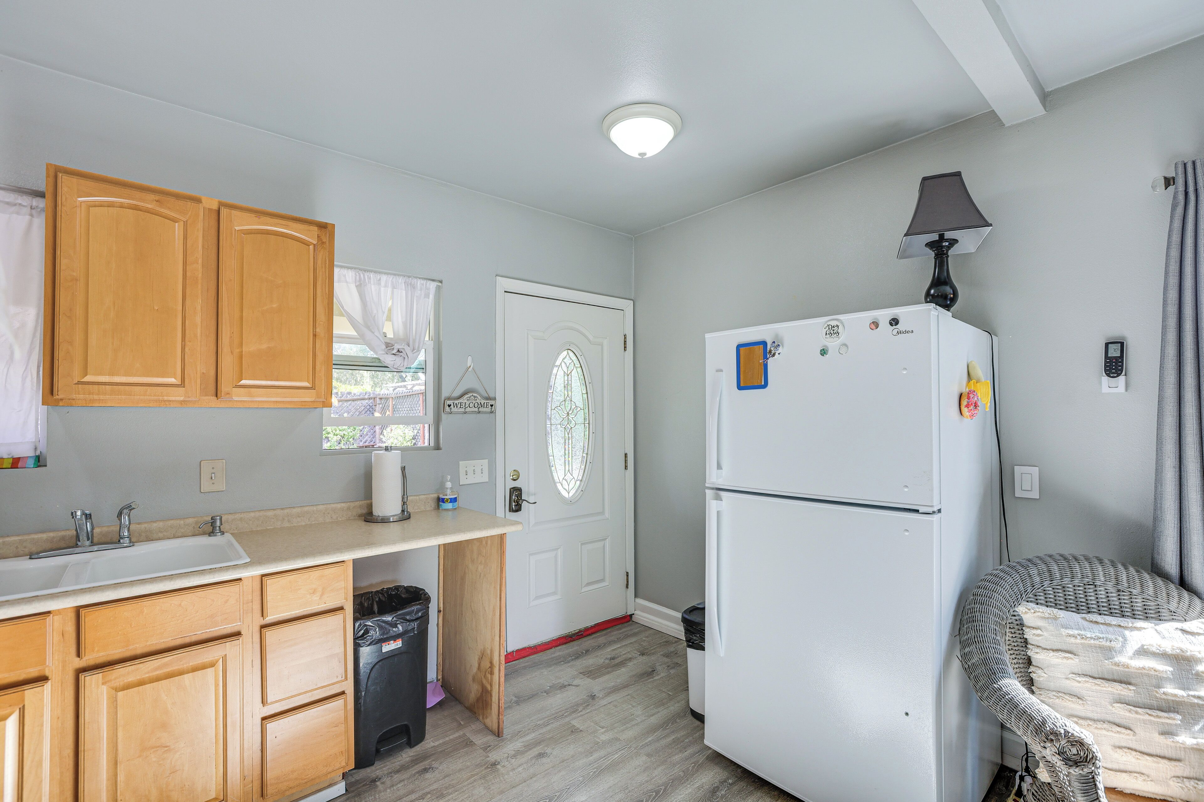 A compact kitchen with wooden cabinets, a white refrigerator, a sink, and a small trash bin.