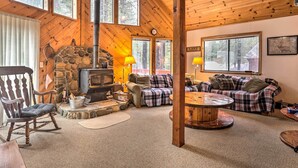 A cozy cabin interior with a stone fireplace, wooden walls, and large windows overlooking a forest. - Truckee Winter Escape 6 Mi to Ski Slopes! (Truckee)