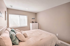 A bedroom with a bed, a dresser, a window, and a wall-mounted picture.