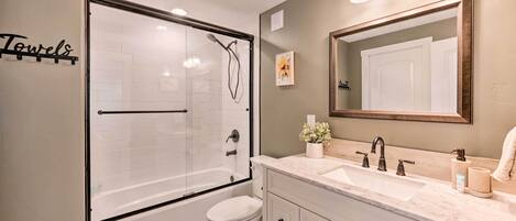 Een moderne badkamer met een douchecabine, een wit toilet, een wastafel met spiegel en een handdoekhouder met de tekst 'Handdoeken'.