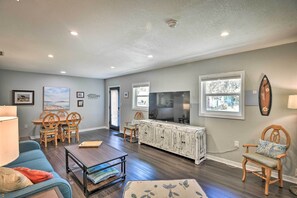 A living room with a blue sofa, wooden chairs, a coffee table, a TV, and a cabinet. - Near Beaches and Speedway! Dog-friendly Hidden Gem (Port Orange)