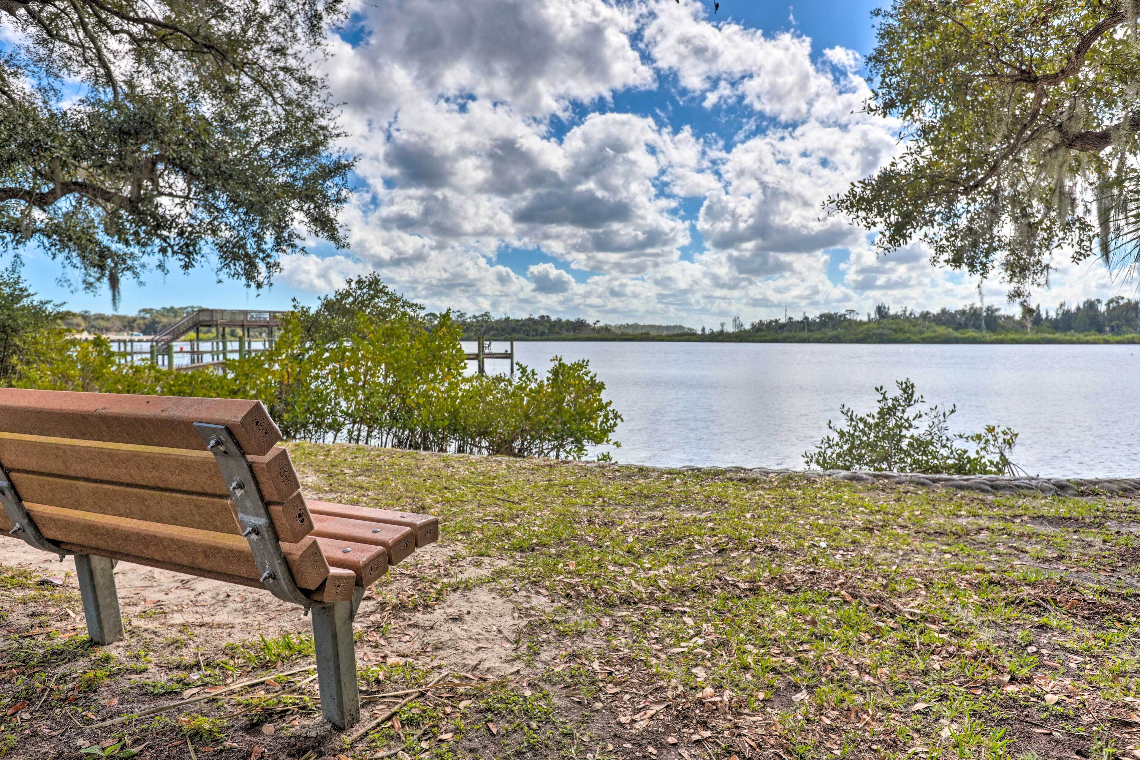 A bench overlooking a lake with a wooden pier in the background.