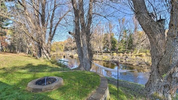 A serene outdoor area with a fire pit, a small pond, and a hammock.
