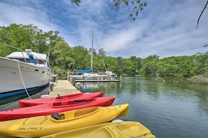 Un muelle con un bote blanco y varias kayaks alineados.