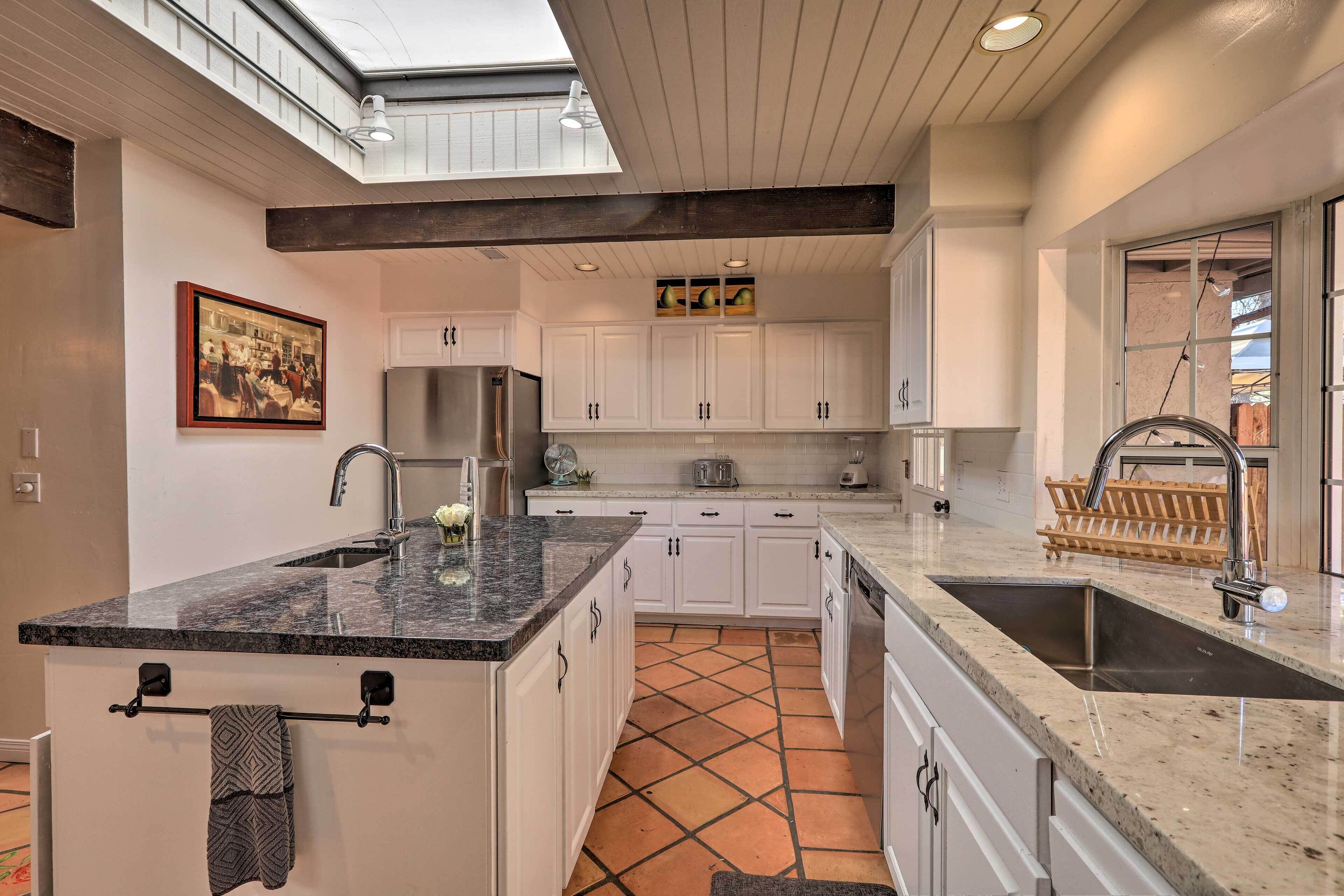 A modern kitchen with white cabinets, a central island, and a skylight.