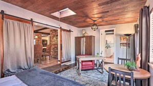 A room with a bed, a dining table with chairs, a small table with a plant, and a brick wall. - Hot Tub & Fire Pit: Sedona Oasis! (Sedona)