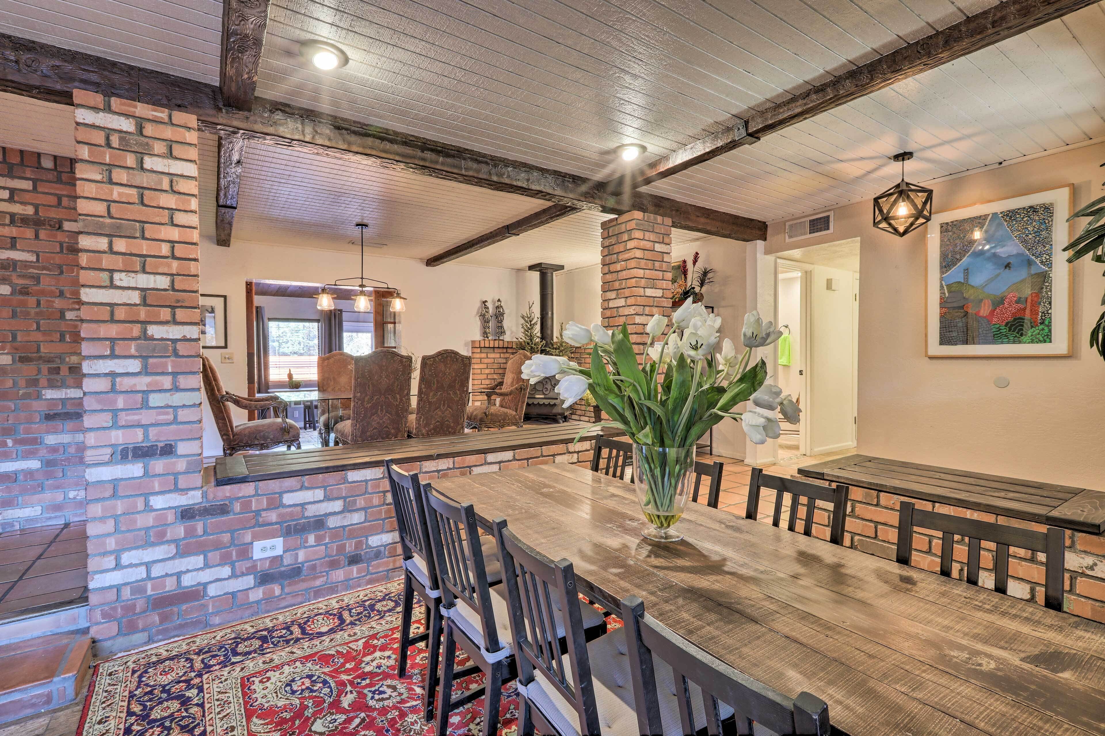 A dining area with a wooden table, chairs, and a brick fireplace.