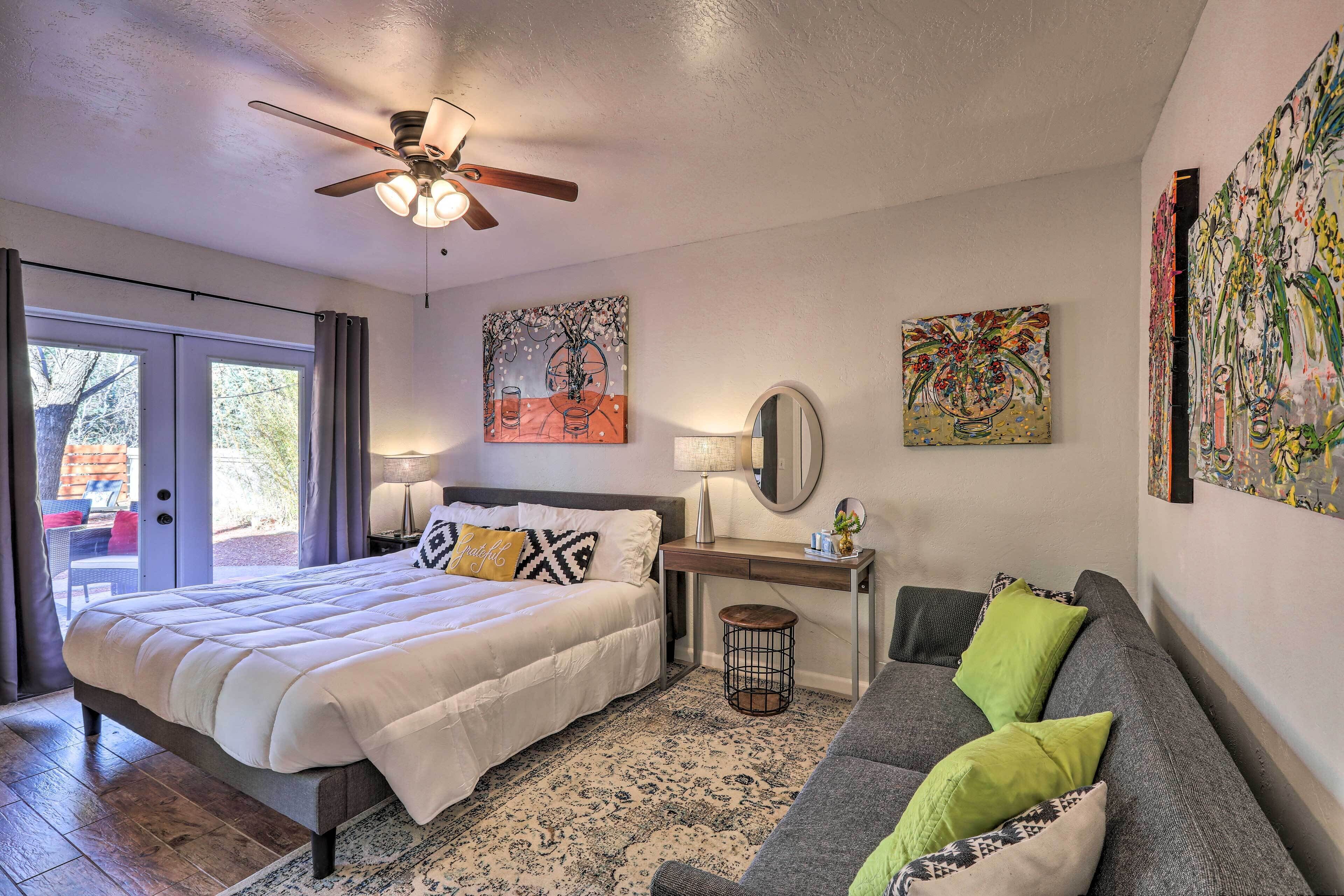 A bedroom with a bed, a desk, a sofa, and artwork on the walls.