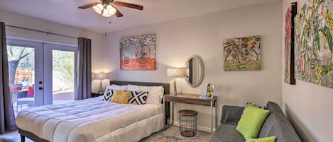 A bedroom with a bed, a desk, a sofa, and artwork on the walls.