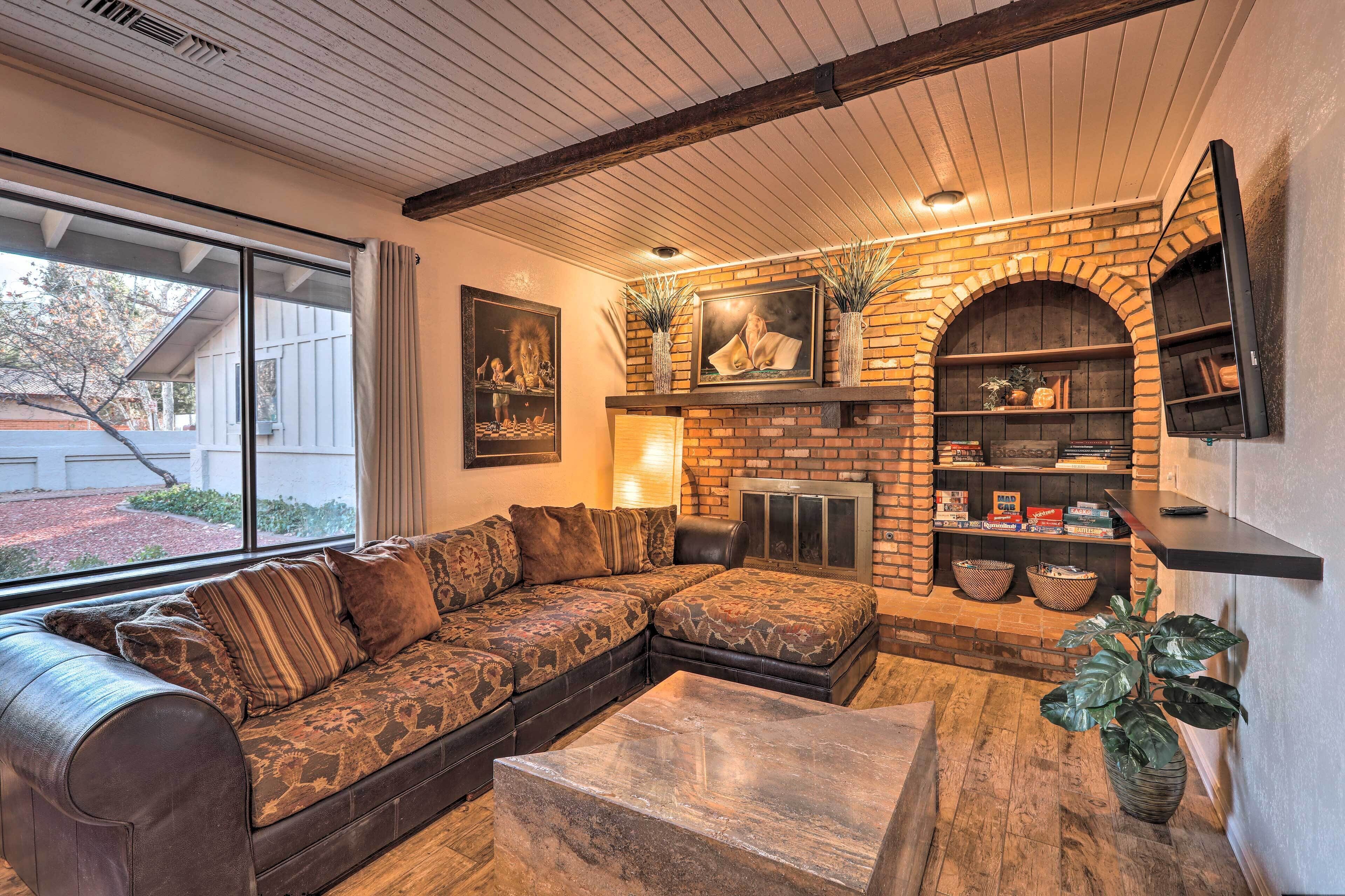 Una sala de estar acogedora con un sofá modular, una chimenea y un televisor montado en la pared.