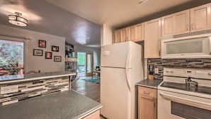 A modern kitchen with a refrigerator, microwave, and stove. There are wooden cabinets and a countertop. - Mountain Lodge w/ Hot Tub, Walk to Grindstone Lake (Ruidoso)