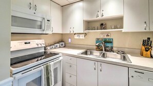 A modern kitchen with white cabinets, a built-in microwave, a stove, and a sink. - Longboat Key Condo W/lanai, Walk to Beach & Shops (Longboat Key)