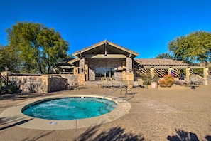 A pool area with a stone building, lounge chairs, and a clear sky.