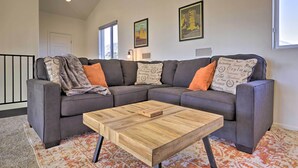 A modern living room with a sectional sofa, a wooden coffee table, and patterned throw pillows. - Modern Pine Retreat w/ Deck & Stunning Views! (Pine)