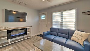A living room with a blue sofa, a coffee table, a fireplace, and a ceiling fan. - Charming Vacation Rental: Close to Downtown! (Sarasota)