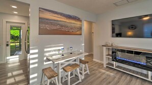 A modern kitchen with a dining area, a large fish tank, and a sunset painting. - Charming Vacation Rental: Close to Downtown! (Sarasota)