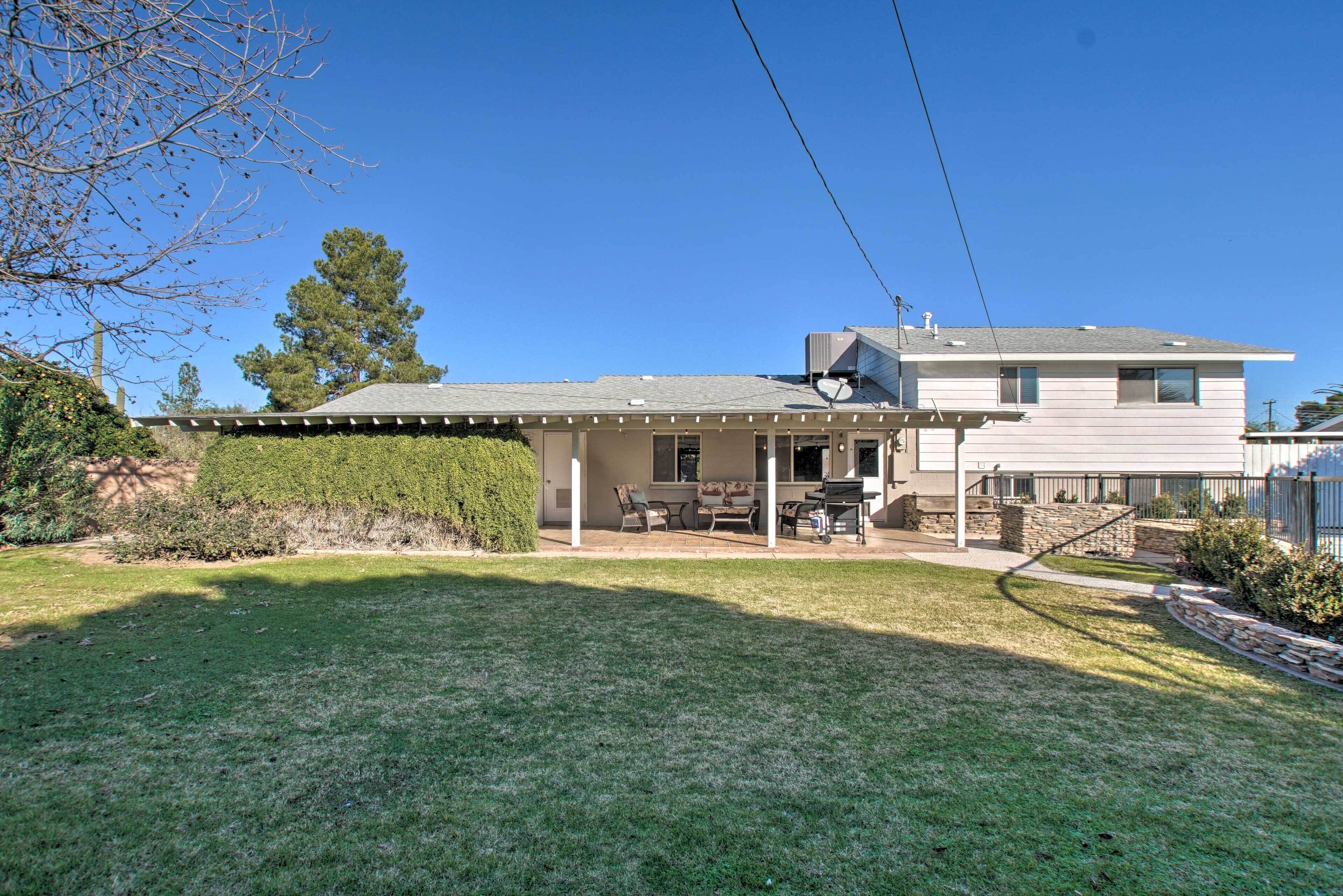 A two-story house with a covered patio, a lawn, and a large tree.