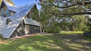 A rustic house with a sloped metal roof, surrounded by a well-maintained lawn and trees.
