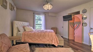 A bedroom with a bed, a chair, a TV, and a door with a mirror.