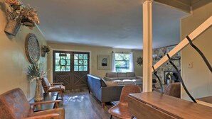 A spacious living room with a wooden dining table, leather chairs, a sofa, and a staircase leading to another level.
