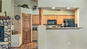 Une cuisine moderne avec des meubles en bois, une cheminée en pierre et un four à micro-ondes encastré.