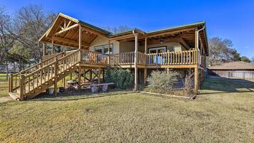 A two-story wooden house with a covered porch and a staircase leading to the upper level.