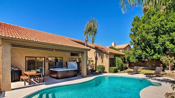A backyard with a swimming pool, a hot tub, and outdoor furniture.