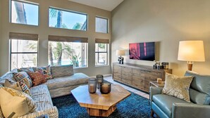 A living room with a sofa, coffee table, and a TV mounted on the wall.