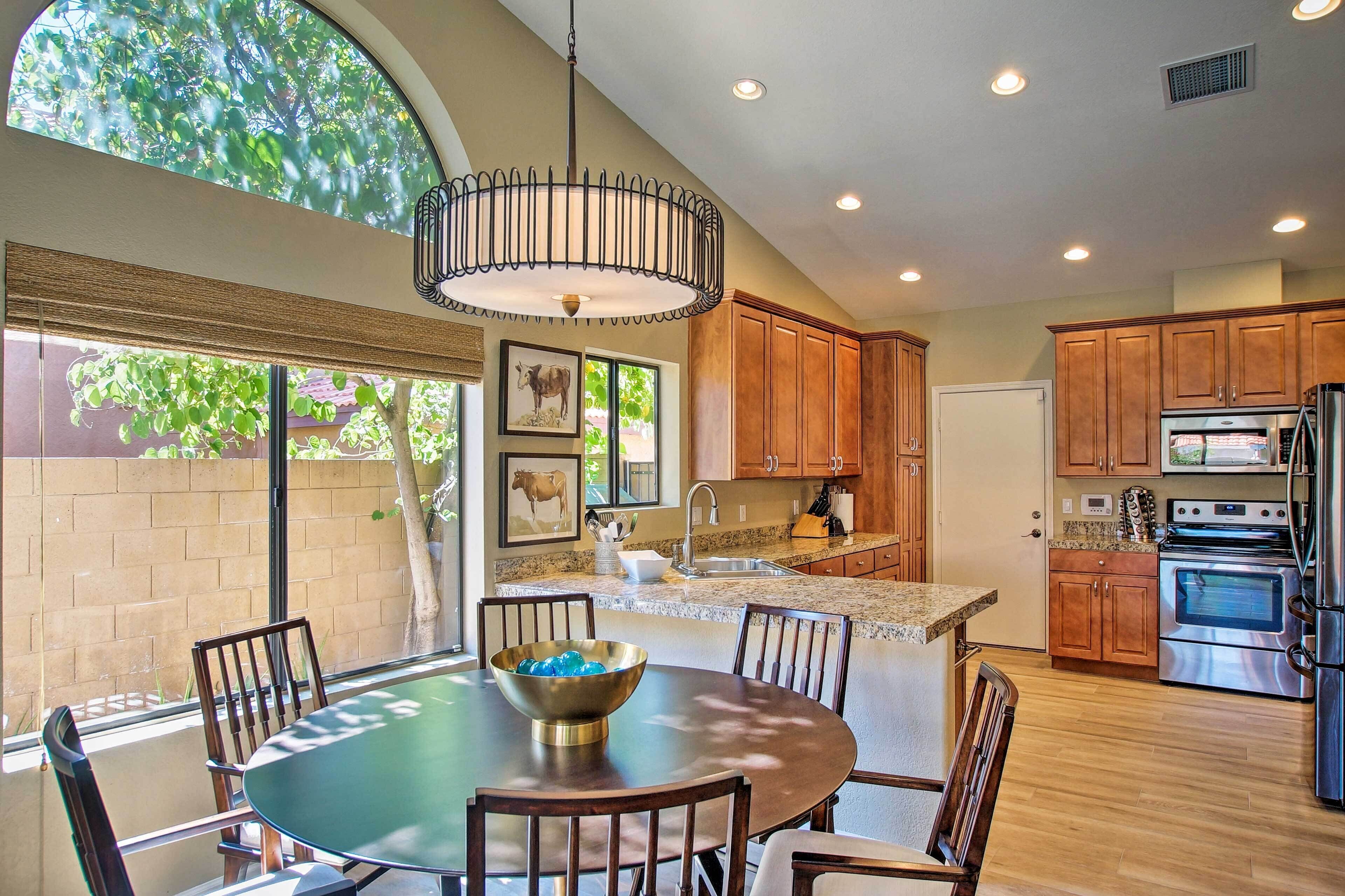 A modern kitchen with wooden cabinets, a stainless steel refrigerator, and a large island with a bowl.