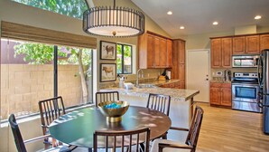 A modern kitchen with wooden cabinets, a stainless steel refrigerator, and a large island with a bowl.
