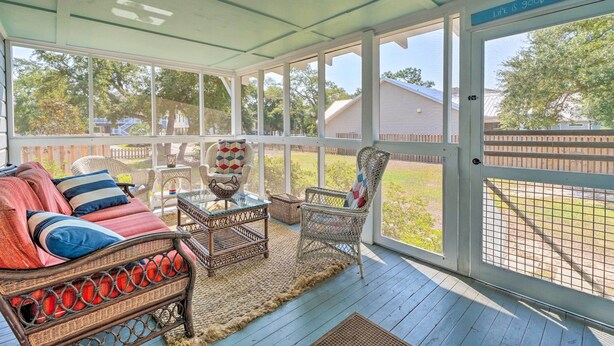 A covered porch with wicker furniture, a cushioned sofa, and a view of a backyard. - Historic Family Home < 1 Mi to Long Beach! (Oak Island)