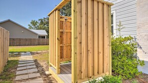 A wooden outdoor shed with a door, a stone pathway leading to it, and a house in the background. - Historic Family Home < 1 Mi to Long Beach! (Oak Island)