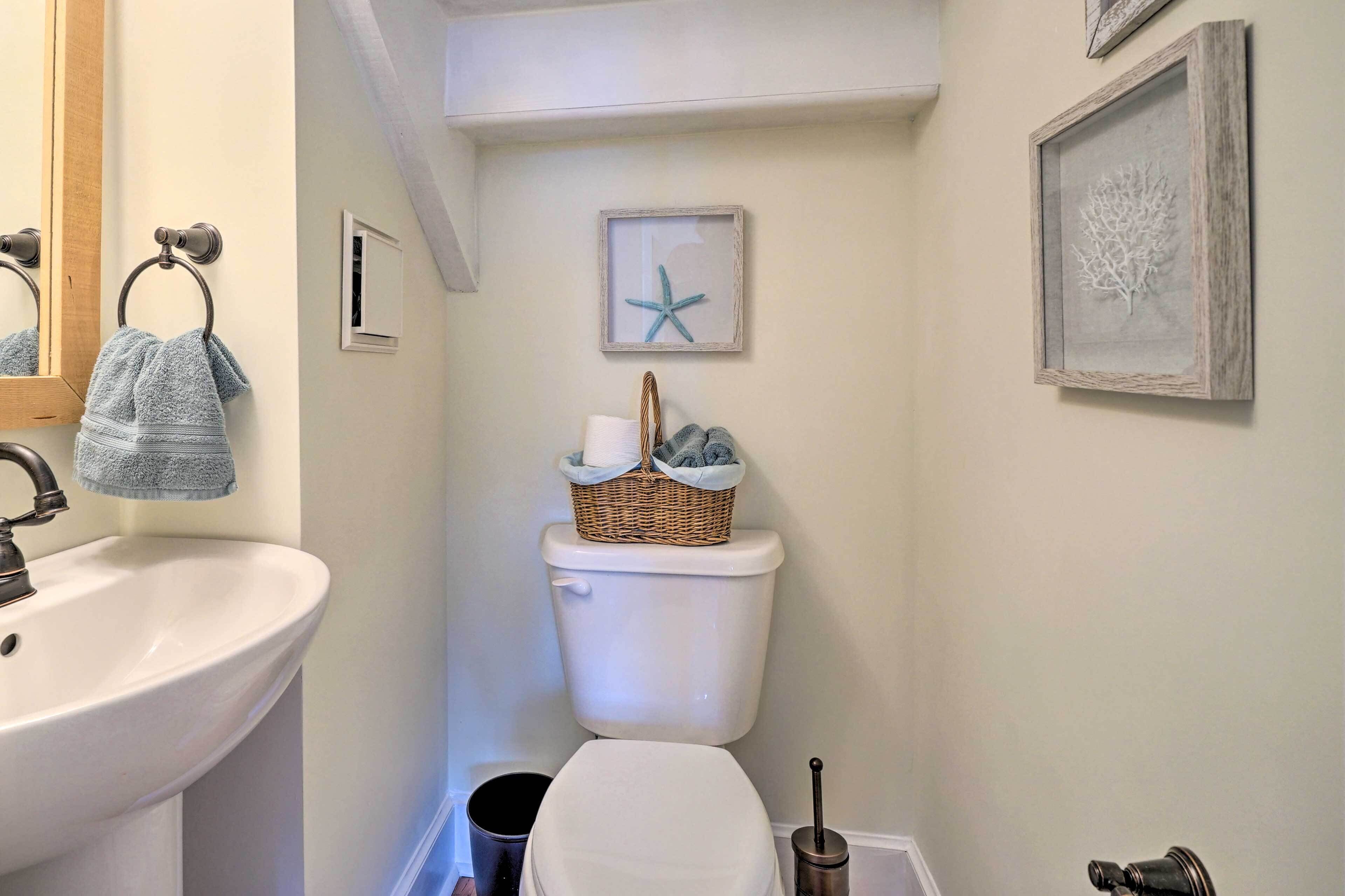 A bathroom with a sink, toilet, and framed artwork on the wall.