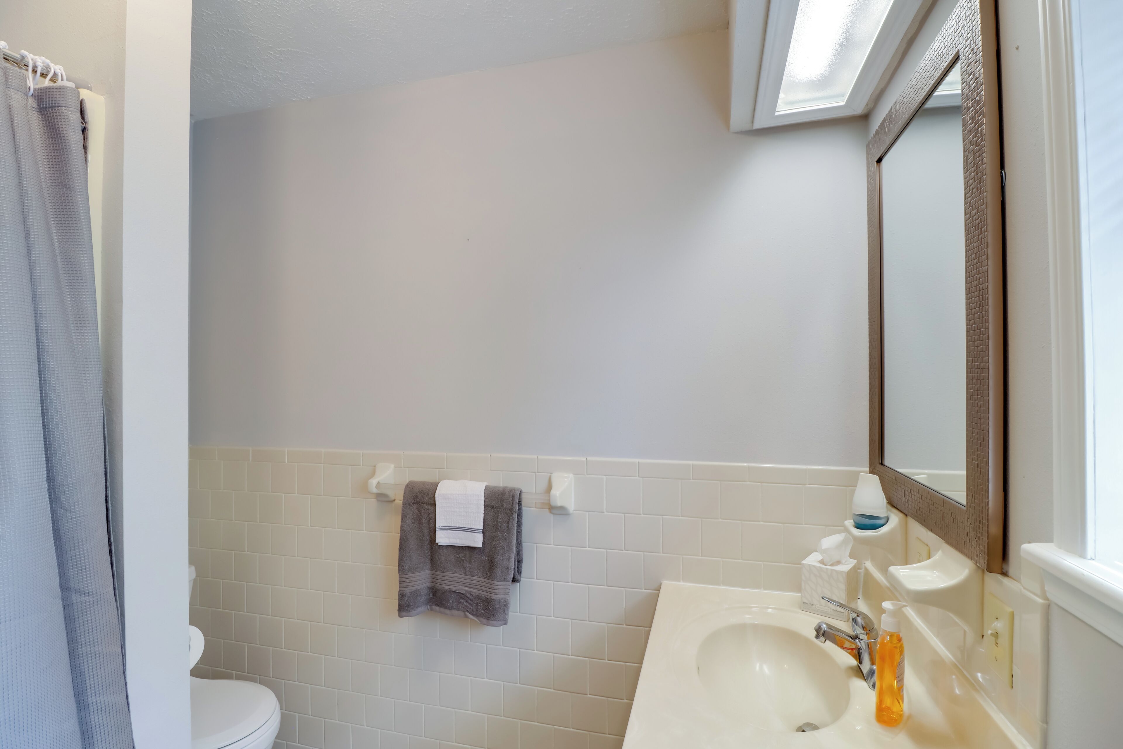 Un baño con inodoro, lavabo y barra para toallas.