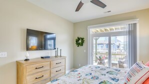 A bedroom with a bed, a dresser, a television, and a balcony with outdoor furniture. - Surf City Home w/ Outdoor Shower: Walk to Beach! (Holly Ridge)