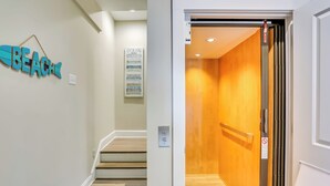 A hallway with a wooden floor, a sign reading "BEACH," and a wooden door with a no-smoking sign. - Surf City Home w/ Outdoor Shower: Walk to Beach! (Holly Ridge)