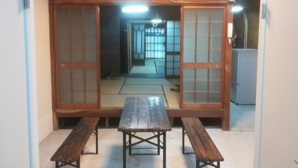 Una habitación japonesa tradicional con suelo de tatami, una mesa de madera y bancos.