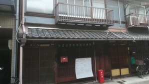 Un edificio tradicional japonés con tejado de tejas, puerta de madera y buzón rojo.
