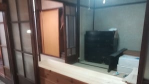 Una habitación con suelo de madera, un mostrador blanco, un armario negro y un electrodoméstico blanco.