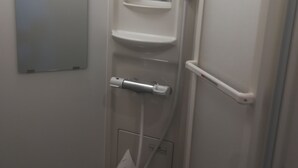 Un baño pequeño y estrecho, con paredes blancas, un espejo, un perchero y una estantería.