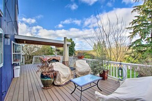 A wooden deck with a covered table and chairs, a potted plant, and a lantern. - Puget Sound Home w/ Beautiful Yard & Deck! (Des Moines)